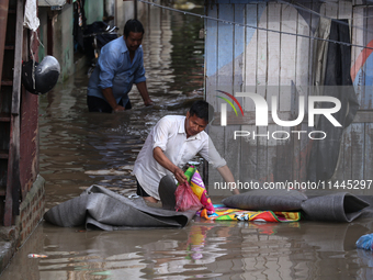 Residents of Kathmandu are wading through the floodwater along the embankment of the Bagmati River flowing through the capital after incessa...