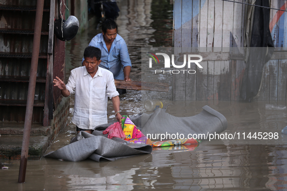 Residents of Kathmandu are wading through the floodwater along the embankment of the Bagmati River flowing through the capital after incessa...