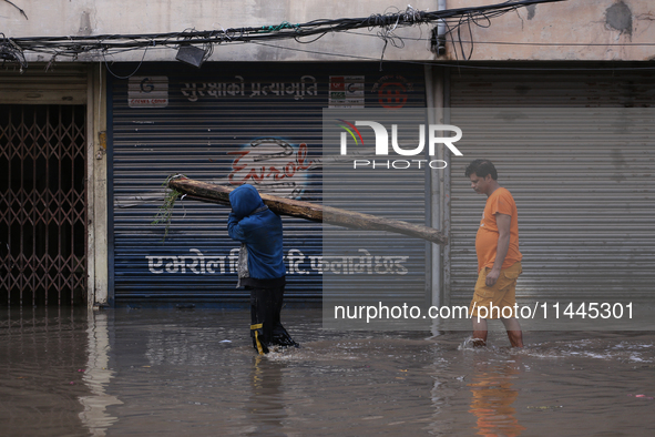 Residents of Kathmandu are wading through the floodwater along the embankment of the Bagmati River flowing through the capital after incessa...