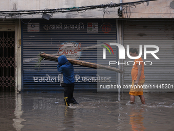 Residents of Kathmandu are wading through the floodwater along the embankment of the Bagmati River flowing through the capital after incessa...