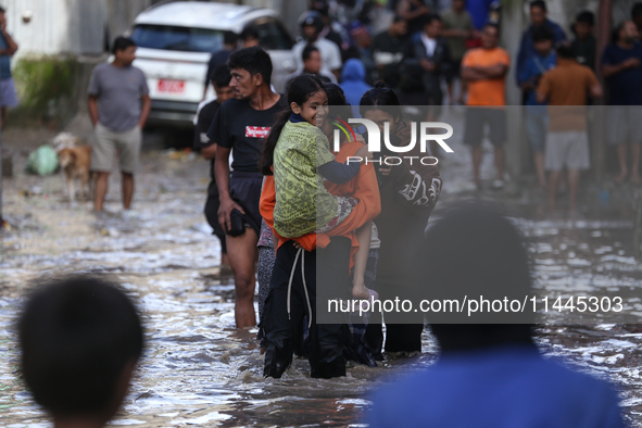 Residents of Kathmandu are wading through the floodwater along the embankment of the Bagmati River flowing through the capital after incessa...