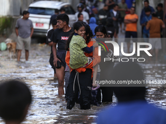 Residents of Kathmandu are wading through the floodwater along the embankment of the Bagmati River flowing through the capital after incessa...