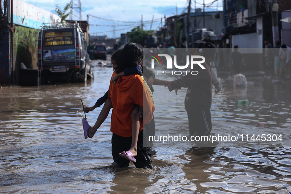 Residents of Kathmandu are wading through the floodwater along the embankment of the Bagmati River flowing through the capital after incessa...