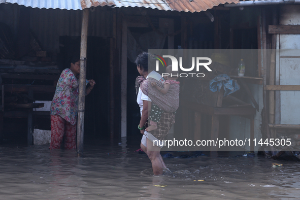 Residents of Kathmandu are wading through the floodwater along the embankment of the Bagmati River flowing through the capital after incessa...