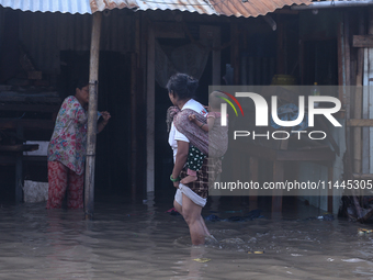 Residents of Kathmandu are wading through the floodwater along the embankment of the Bagmati River flowing through the capital after incessa...