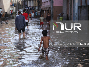 Residents of Kathmandu are wading through the floodwater along the embankment of the Bagmati River flowing through the capital after incessa...