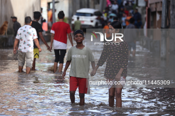 Residents of Kathmandu are wading through the floodwater along the embankment of the Bagmati River flowing through the capital after incessa...