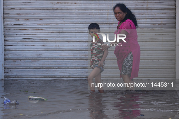 Residents of Kathmandu are wading through the floodwater along the embankment of the Bagmati River flowing through the capital after incessa...