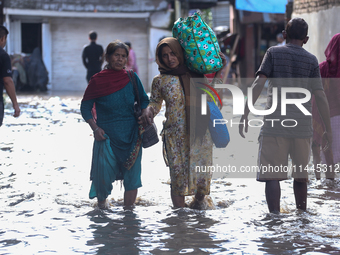 Residents of Kathmandu are wading through the floodwater along the embankment of the Bagmati River flowing through the capital after incessa...