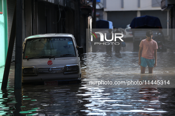 Residents of Kathmandu are wading through the floodwater along the embankment of the Bagmati River flowing through the capital after incessa...