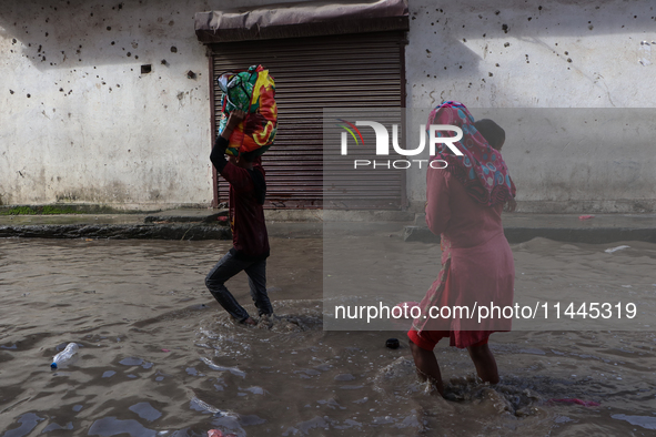 Residents of Kathmandu are wading through the floodwater along the embankment of the Bagmati River flowing through the capital after incessa...