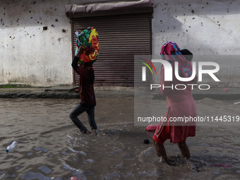 Residents of Kathmandu are wading through the floodwater along the embankment of the Bagmati River flowing through the capital after incessa...