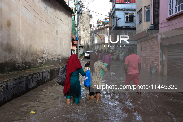 Residents of Kathmandu are wading through the floodwater along the embankment of the Bagmati River flowing through the capital after incessa...