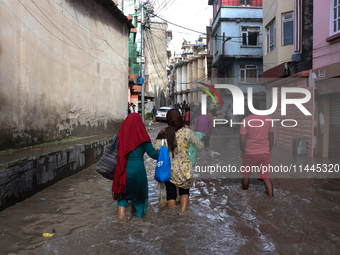 Residents of Kathmandu are wading through the floodwater along the embankment of the Bagmati River flowing through the capital after incessa...