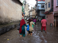 Residents of Kathmandu are wading through the floodwater along the embankment of the Bagmati River flowing through the capital after incessa...