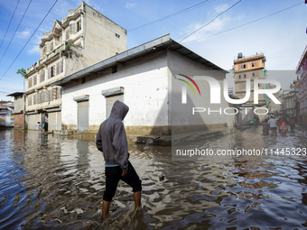 A Nepali man is wading through the flooded water in Nepal on July 31, 2024. (