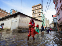 A woman in Nepal is carrying a baby while wading through the flood in Kathmandu, Nepal, on July 6, 2024. (