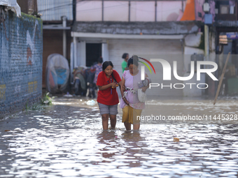 People are wading through the flood in a slum in Kathmandu, Nepal, on July 31, 2024. (