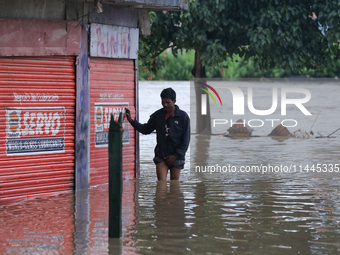 A Nepali man is wading through the flooded water in Nepal on July 31, 2024. (