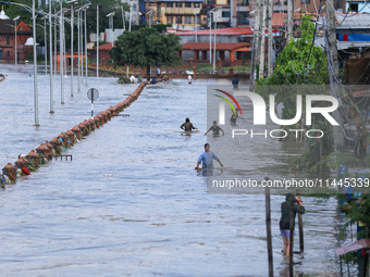 People are wading through the flood in a slum in Kathmandu, Nepal, on July 31, 2024. (