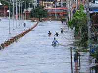 People are wading through the flood in a slum in Kathmandu, Nepal, on July 31, 2024. (