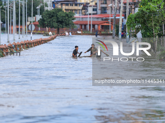 People are wading through the flood in a slum in Kathmandu, Nepal, on July 31, 2024. (