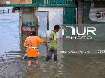 People are wading through the flood in a slum in Kathmandu, Nepal, on July 31, 2024. (