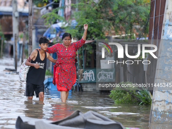 People are wading through the flood in a slum in Kathmandu, Nepal, on July 31, 2024. (