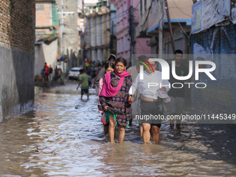 People are wading through the flood in a slum in Kathmandu, Nepal, on July 31, 2024. (