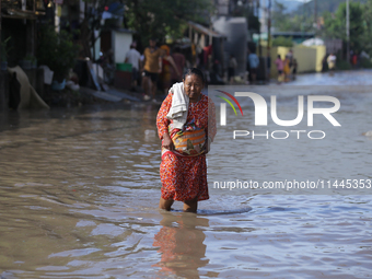 A Nepali woman is wading through the flooded water in Nepal on July 31, 2024. (