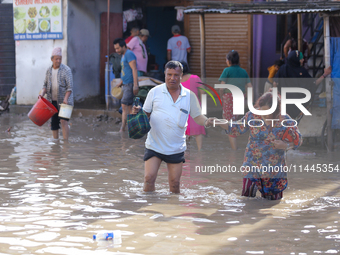 People are wading through the flood in a slum in Kathmandu, Nepal, on July 31, 2024. (