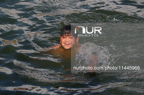 A child is taking a bath in Dal Lake on a hot summer day in Srinagar, Jammu and Kashmir, on July 31, 2024. 