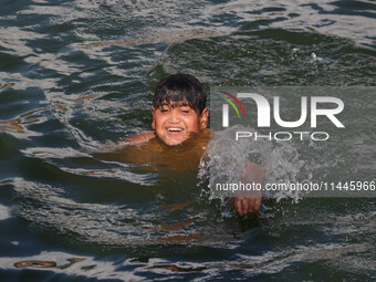 A child is taking a bath in Dal Lake on a hot summer day in Srinagar, Jammu and Kashmir, on July 31, 2024. (