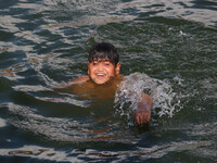 A child is taking a bath in Dal Lake on a hot summer day in Srinagar, Jammu and Kashmir, on July 31, 2024. (