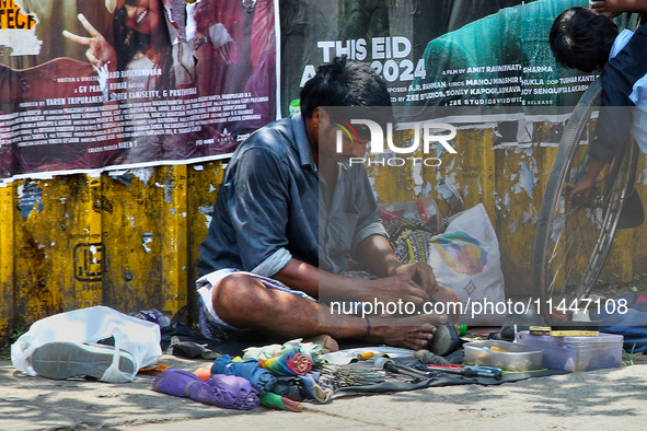 A cobbler is repairing shoes along the footpath in the East Fort area of Thiruvananthapuram (Trivandrum), Kerala, India, on April 13, 2024. 