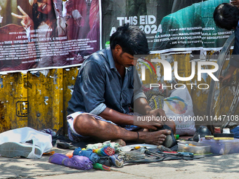 A cobbler is repairing shoes along the footpath in the East Fort area of Thiruvananthapuram (Trivandrum), Kerala, India, on April 13, 2024....