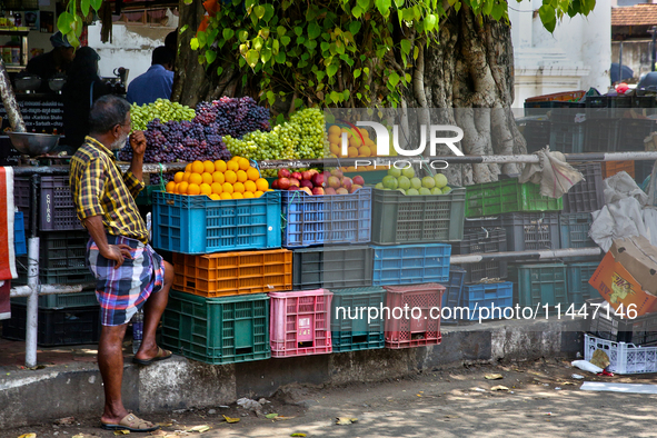 A man is waiting by a fruit stand in the East Fort area of Thiruvananthapuram (Trivandrum), Kerala, India, on April 13, 2024. 