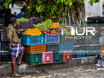 A man is waiting by a fruit stand in the East Fort area of Thiruvananthapuram (Trivandrum), Kerala, India, on April 13, 2024. (