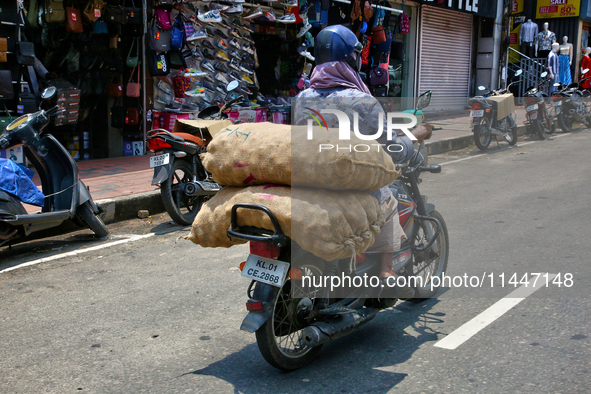 A man is carrying sacks filled with potatoes on his motorbike in Thiruvananthapuram (Trivandrum), Kerala, India, on April 13, 2024. 