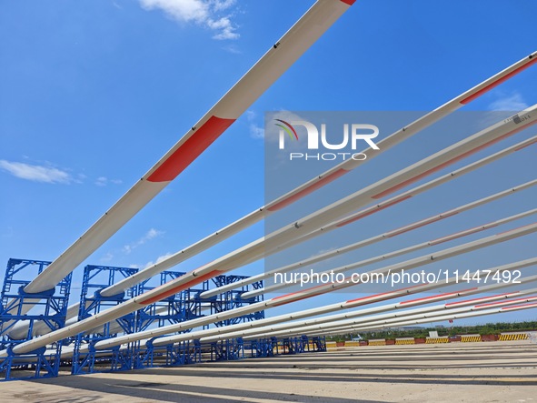 Blades of offshore wind turbines are waiting to be loaded at Penglai Port area of Yantai Port in Yantai, China, on July 31, 2024. On July 31...