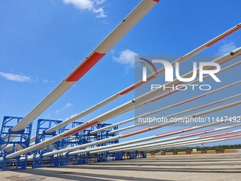 Blades of offshore wind turbines are waiting to be loaded at Penglai Port area of Yantai Port in Yantai, China, on July 31, 2024. On July 31...