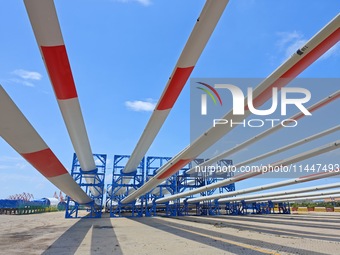 Blades of offshore wind turbines are waiting to be loaded at Penglai Port area of Yantai Port in Yantai, China, on July 31, 2024. On July 31...