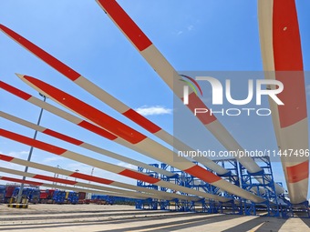 Blades of offshore wind turbines are waiting to be loaded at Penglai Port area of Yantai Port in Yantai, China, on July 31, 2024. On July 31...