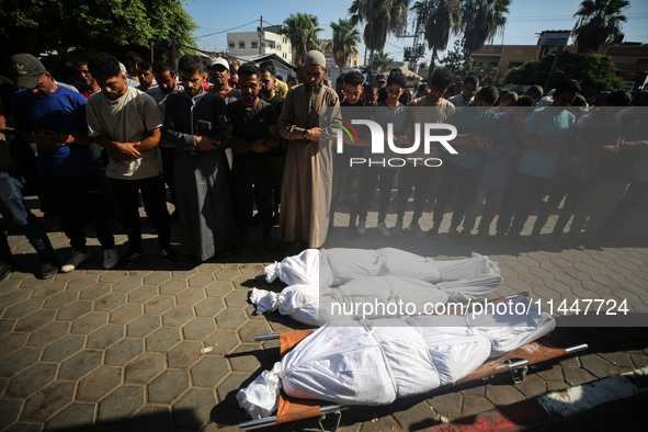 Palestinian men are praying over victims killed in an Israeli strike at the Aqsa Martyrs hospital in Deir el-Balah, on August 1, 2024, amid...