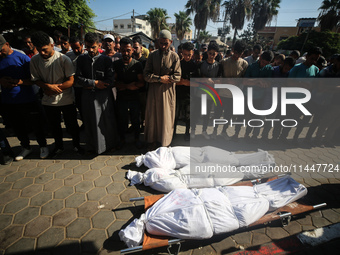 Palestinian men are praying over victims killed in an Israeli strike at the Aqsa Martyrs hospital in Deir el-Balah, on August 1, 2024, amid...