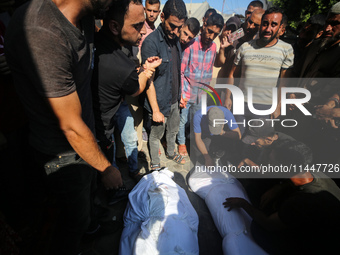 Palestinian men are praying over victims killed in an Israeli strike at the Aqsa Martyrs hospital in Deir el-Balah, on August 1, 2024, amid...