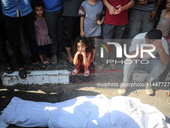 Palestinian men are praying over victims killed in an Israeli strike at the Aqsa Martyrs hospital in Deir el-Balah, on August 1, 2024, amid...