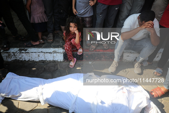 Palestinian men are praying over victims killed in an Israeli strike at the Aqsa Martyrs hospital in Deir el-Balah, on August 1, 2024, amid...