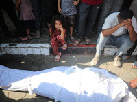 Palestinian men are praying over victims killed in an Israeli strike at the Aqsa Martyrs hospital in Deir el-Balah, on August 1, 2024, amid...