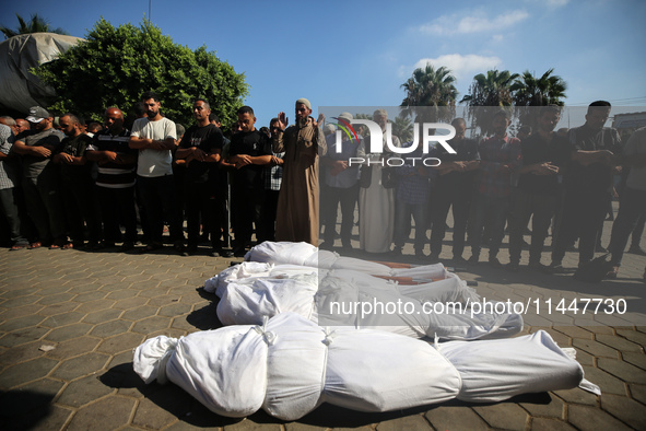 Palestinian men are praying over victims killed in an Israeli strike at the Aqsa Martyrs hospital in Deir el-Balah, on August 1, 2024, amid...